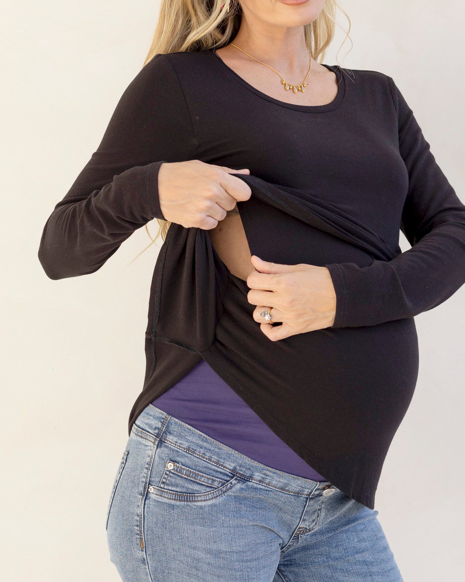 Woman wearing a black long-sleeve nursing top holding her pregnant belly.