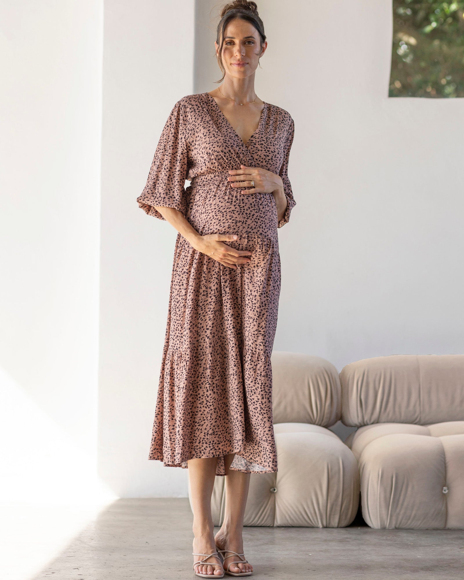 A pregnant woman wearing a brown leaf print maternity maxi dress with a crossover V-neckline and 3/4 puff sleeves.