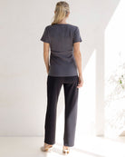 Person wearing a gray outfit with wide-leg pants in a bright room.