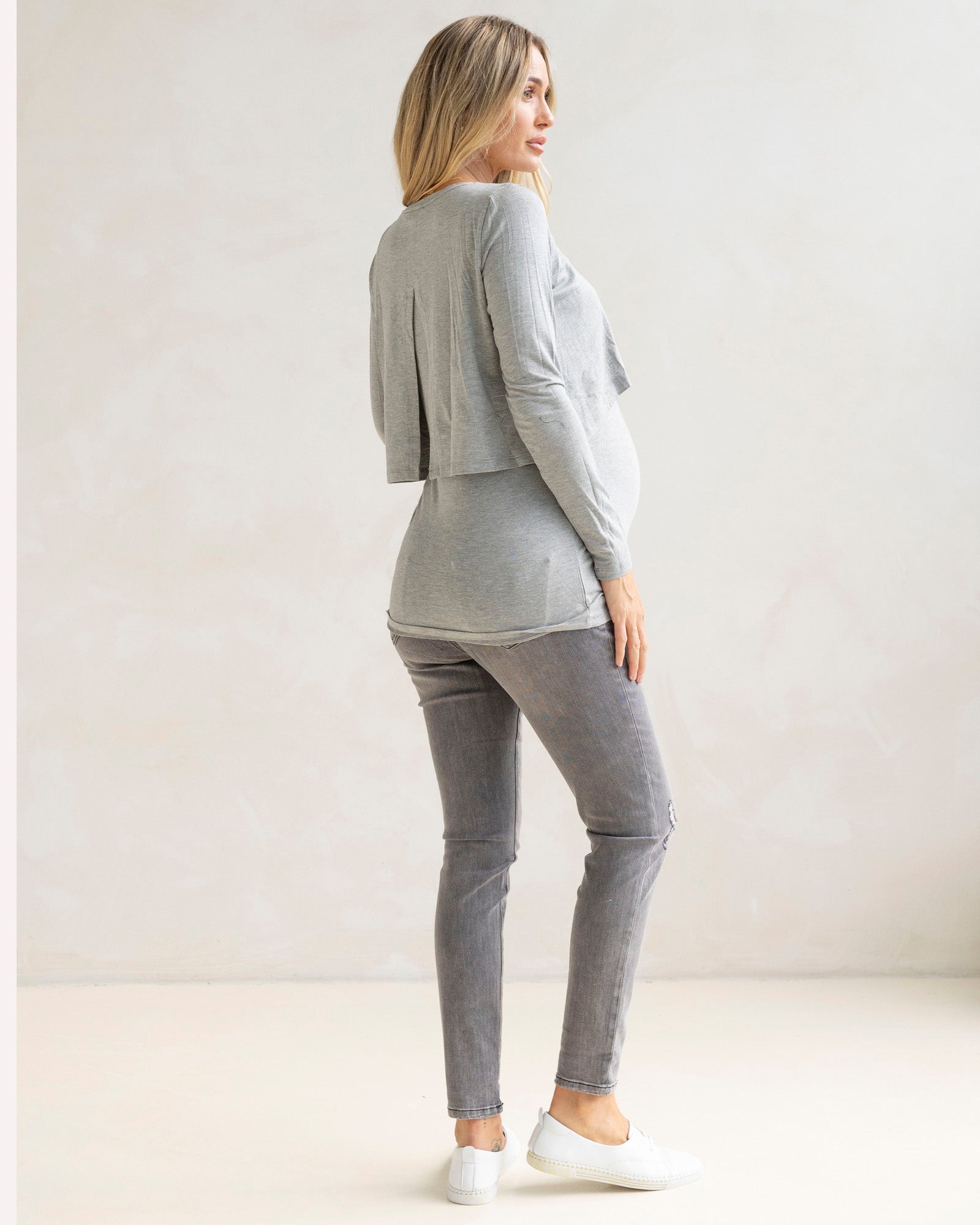 Woman wearing a gray outfit with a long-sleeve top and pants on a white background