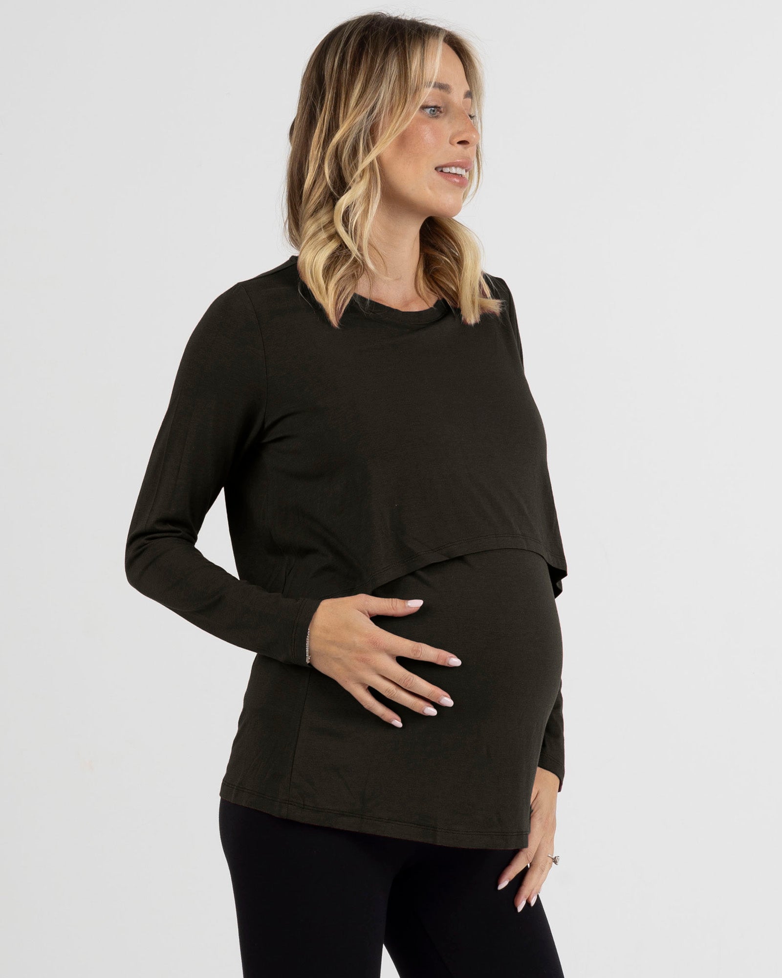 Woman wearing a black long-sleeve maternity top against a white background