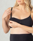 Woman wearing a black nursing bra against a plain background