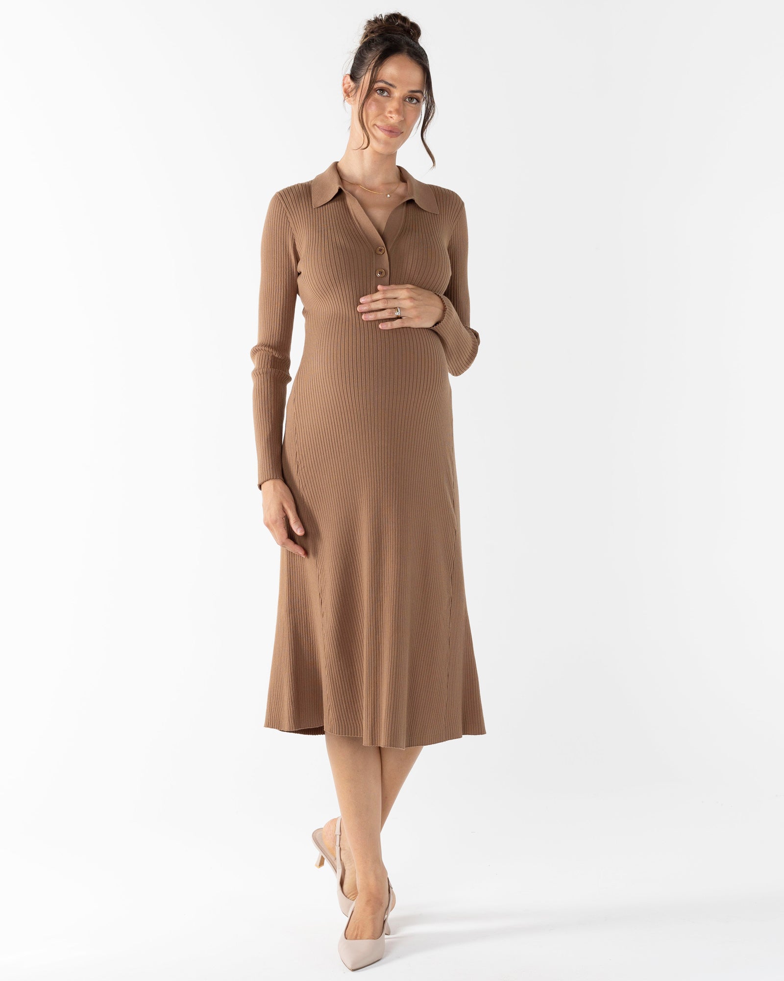A woman wearing a brown long sleeve knitted maternity midi dress with a collar and buttoned front easy for breastfeeding.