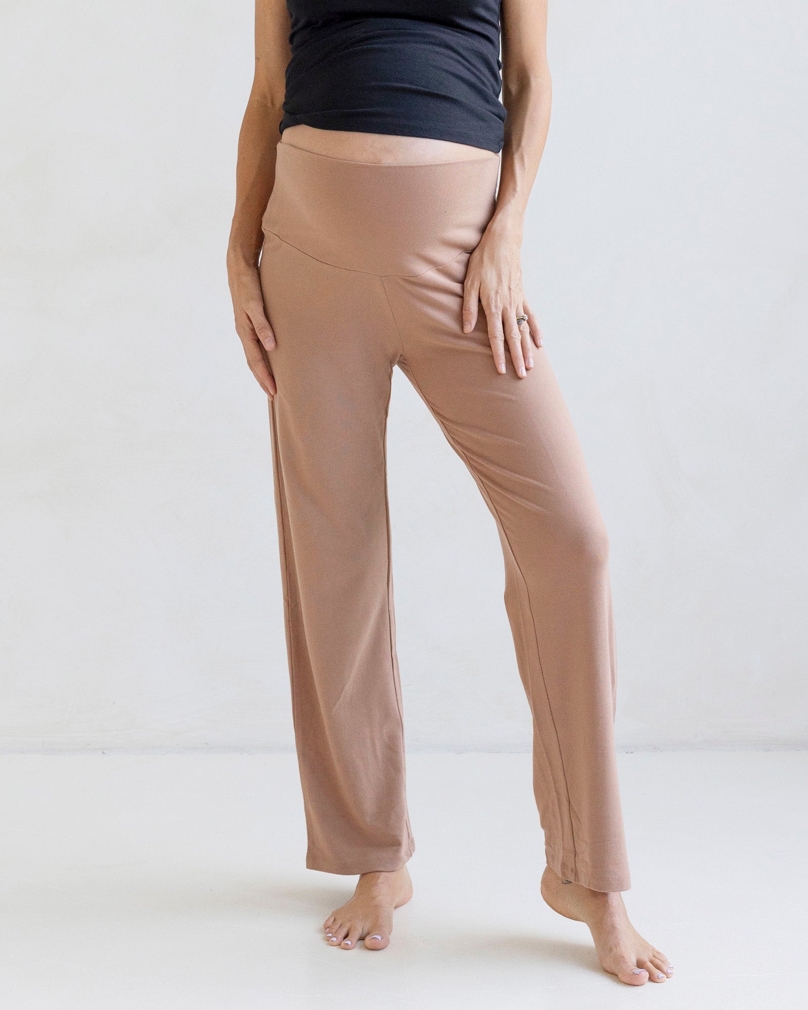Person wearing beige maternity lounge pants and a black maternity singlet top