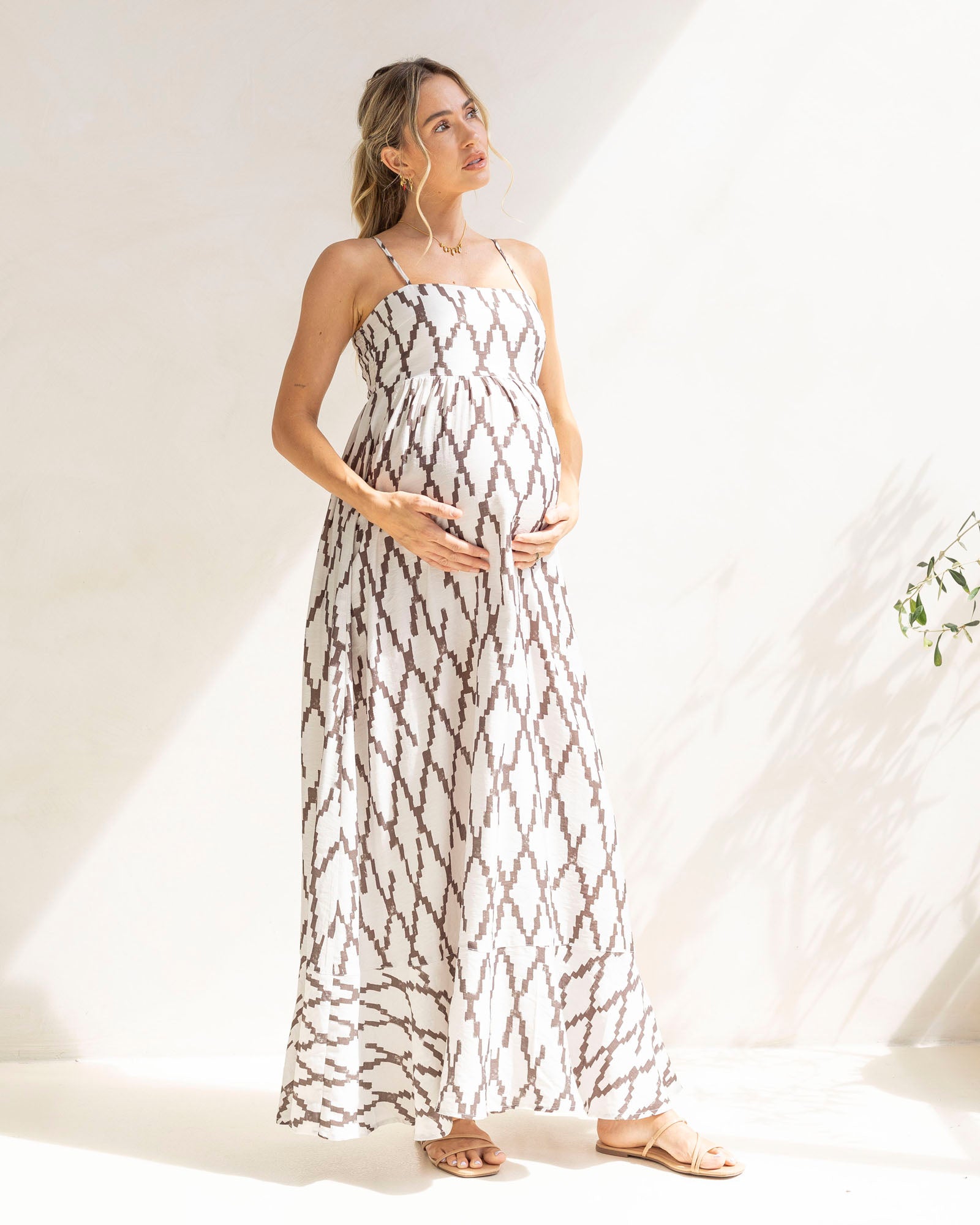Woman wearing a white link print maternity maxi dress with brown pattern against