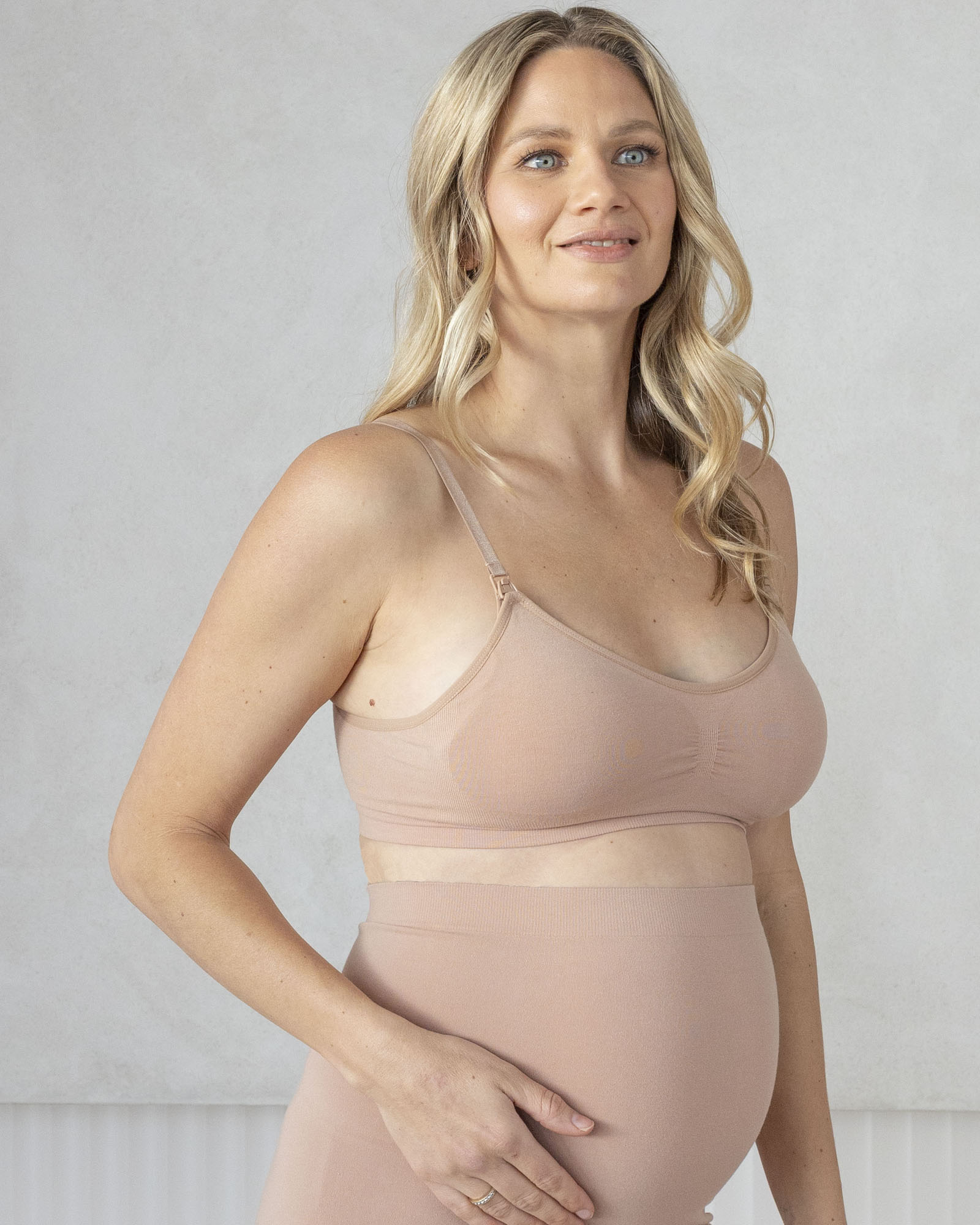 Woman wearing a beige maternity support bra with nursing access and high waist maternity underwear in soft bamboo fabric