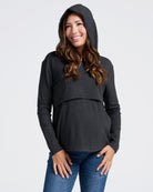 Woman wearing a black maternity hoodie and blue jeans on a white background
