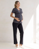 Woman wearing a gray maternity work top and black maternity high waist pants in office