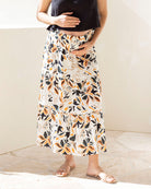 Person wearing a floral maternity skirt with a plain background