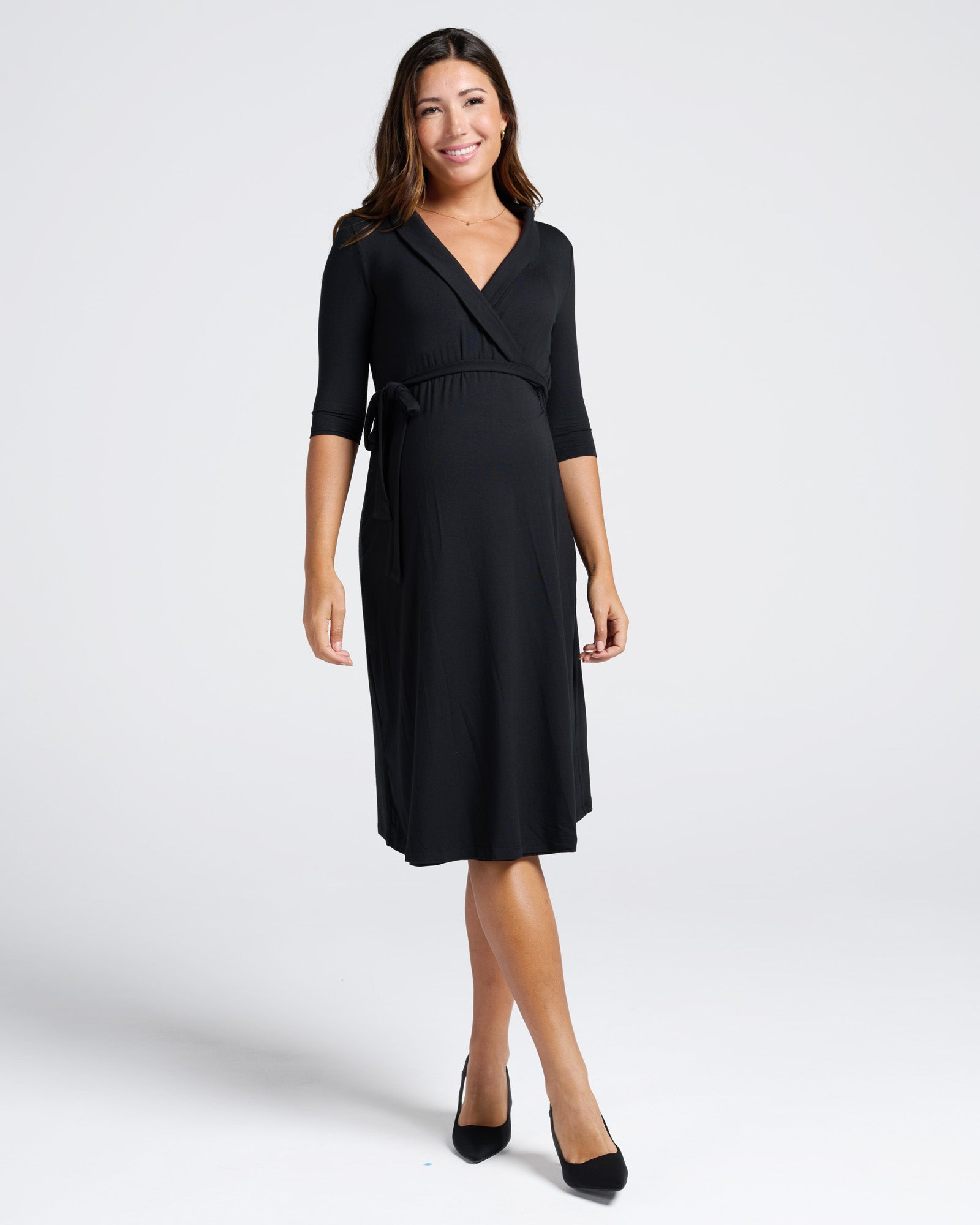 Woman wearing a black maternity work dress on a white background