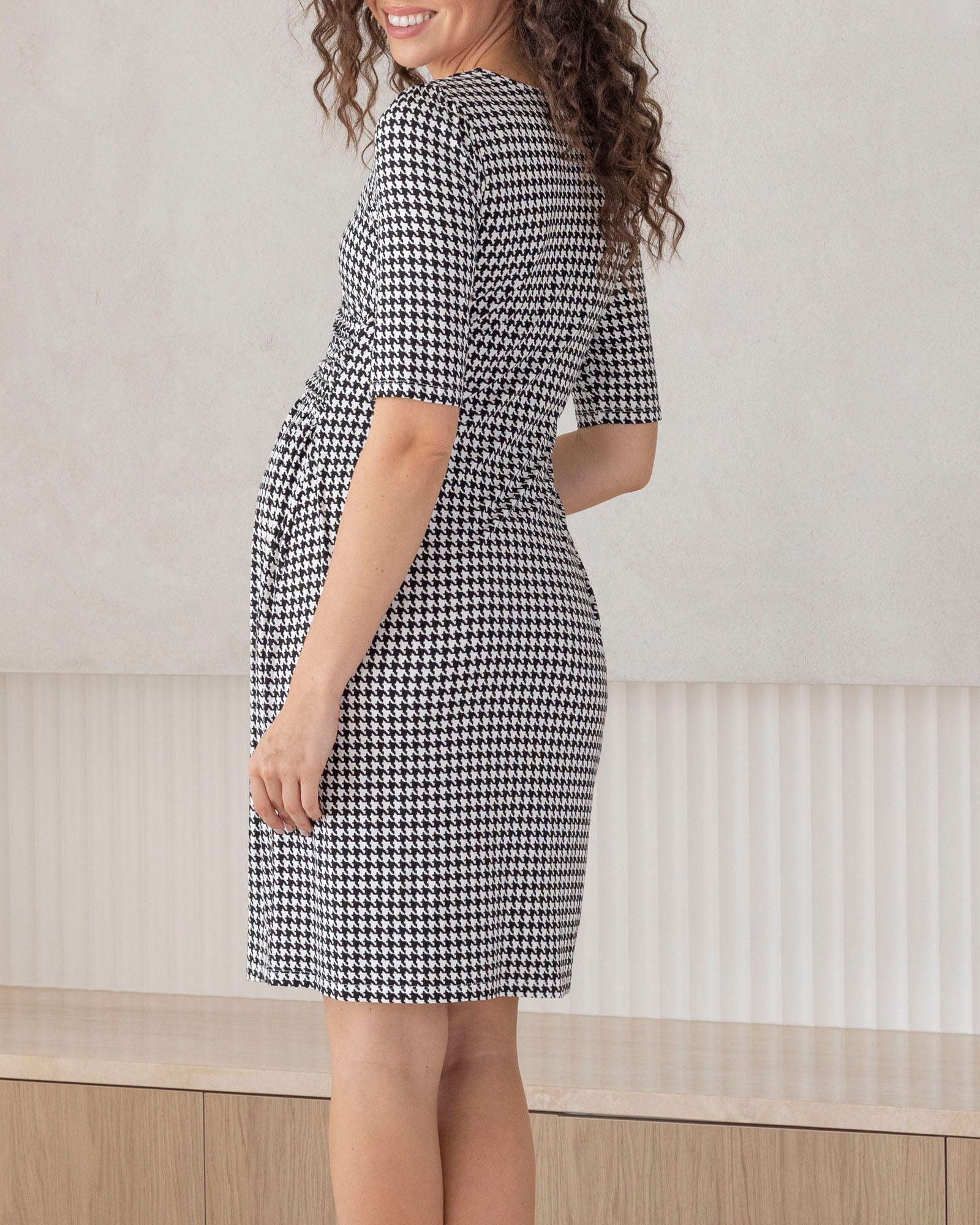 working mum wearing a black and white checkered  maternity dress in office