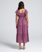 Woman wearing a purple checkered dress with ruffled sleeves on a white background