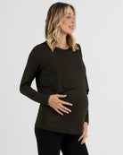 Woman wearing a black long-sleeve maternity top against a white background