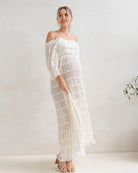 Woman wearing a white off-shoulder maternity dress at home in baby shower event