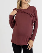 Woman wearing a burgundy long-sleeve breastfeeding top on a white background