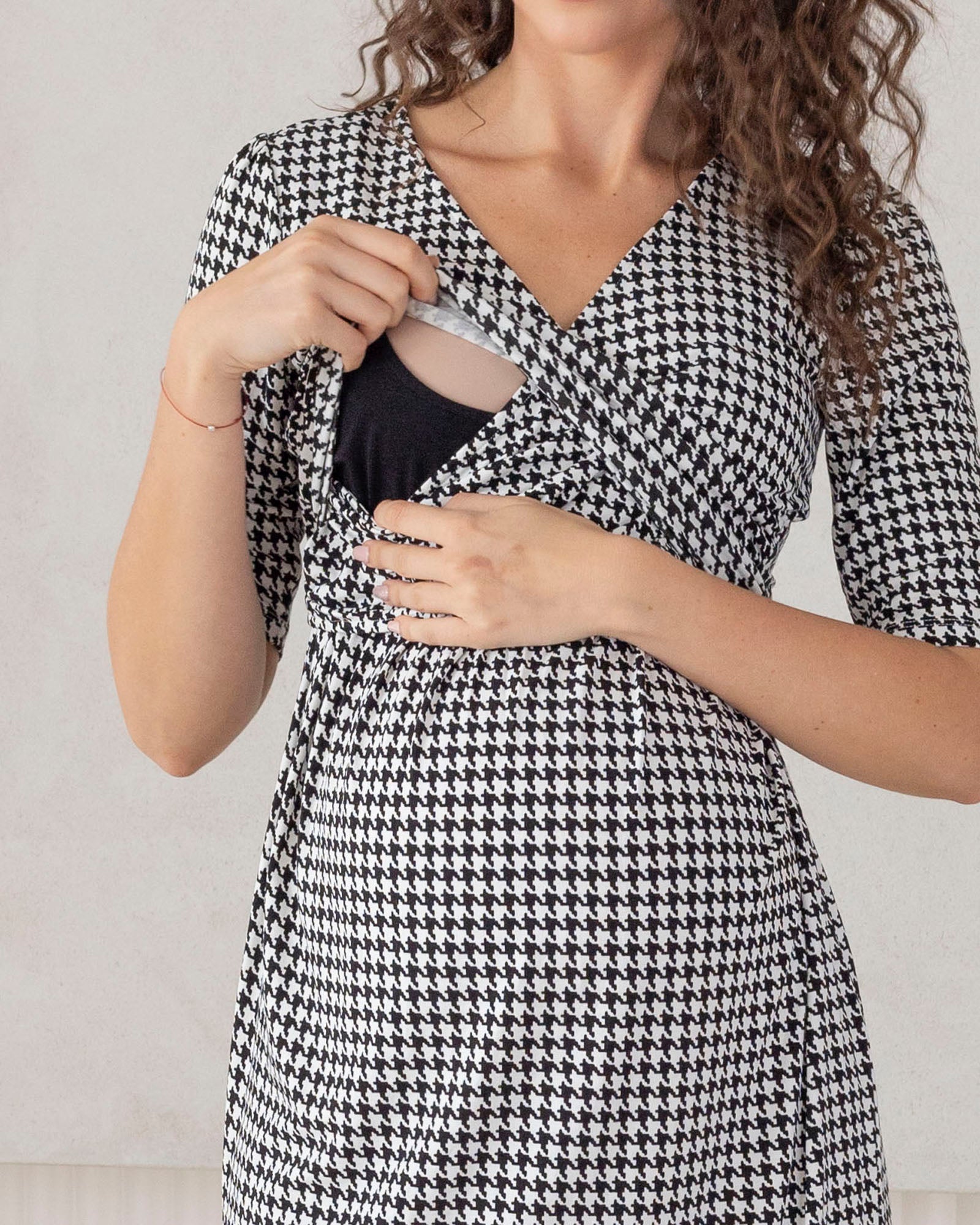 Woman wearing a black and white houndstooth patterned dress against a plain background