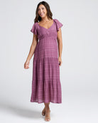 Woman wearing a purple  maternity dress on a white background