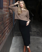 A woman in black and brown angel maternity 2 piece knitted cropped top and skirt set standing against the wall, front (6656401145959)