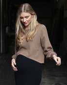 A woman in black and brown angel maternity 2 piece knitted cropped top and skirt set standing against the wall, side2 (6656401145959)
